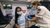 A medic with Israel's Magen David Adom emergency service administers a booster shot of a COVID-19 vaccine to a woman in Tel Aviv, Aug. 14, 2021. 