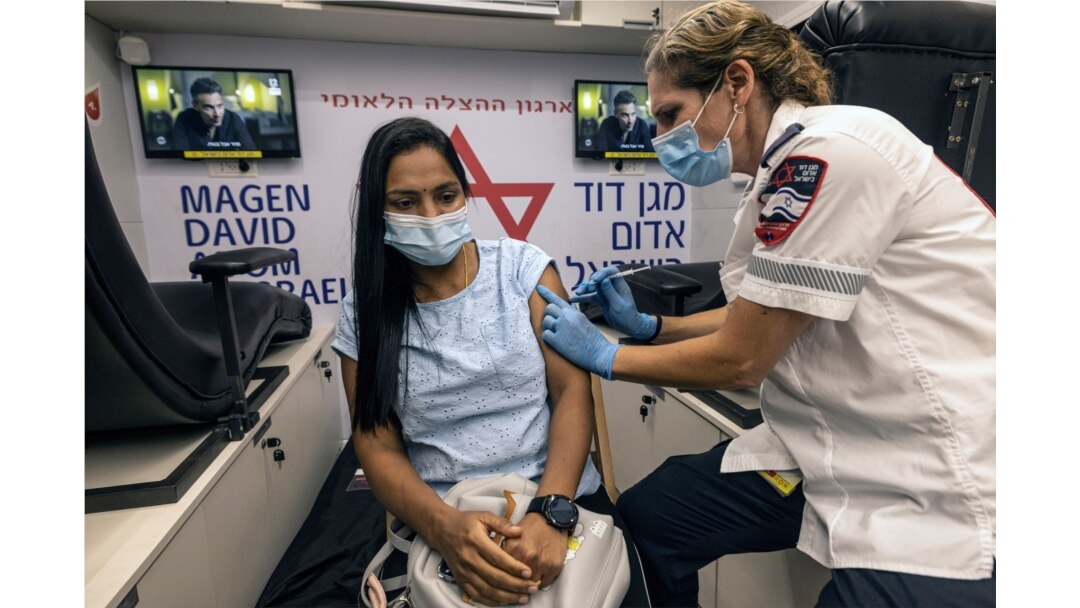 FILE - A medic with Israel's Magen David Adom emergency service administers a booster shot of a COVID-19 vaccine to a woman in Tel Aviv, Aug. 14, 2021.