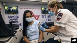 A medic with Israel's Magen David Adom emergency service administers a booster shot of a COVID-19 vaccine to a woman in Tel Aviv, Aug. 14, 2021. 