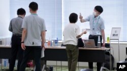 Employees of the beverage maker Suntory register to receive shots of the Moderna COVID-19 vaccine at their office building as the company began its workplace vaccination, June 21, 2021, in Tokyo.