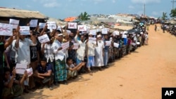 Rohingya refugees holding placards await the arrival of a U.N. Security Council team at the Kutupalong Rohingya refugee camp in Kutupalong, Bangladesh, April 29, 2018. A U.N. Security Council team visiting Bangladesh promised Sunday to work hard to resolve a crisis involving hundreds of thousands of Rohingya Muslims who have fled to the country to escape military-led violence in Myanmar. 