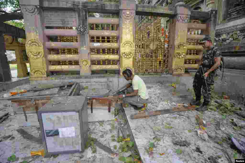 Indian security personnel inspect the site of an explosion inside the Mahabodhi temple complex at Bodh Gaya in the eastern Indian state of Bihar, July 7, 2013. 