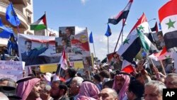 Des partisans du président syrien Bashar Assad protestent contre la décision du président Donald Trump de reconnaître la souveraineté israélienne sur le plateau du Golan, à Homs, en Syrie, mardi, mars 26, 2019. (SANA via AP)