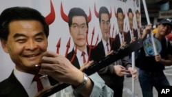 A protester raises a poster depicting outgoing Chief Executive Leung Chun-ying, left, with devil horns during a rally on the first day of 2017 in Hong Kong, Jan. 1, 2017.