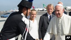 Paus Fransiskus didampigi oleh CEO Alitalia dan pemimpin Luca Cordero di Montezemolo (dua dari kanan) dan putrinya Guia, disambut oleh pejabat paramiliter Italia Carabinieri (kiri) di bandara internasional Fiumicino, Roma, saat berjalan menuju pesawat yang akan menerbangkannya ke La Habana, Kuba (19/9). 