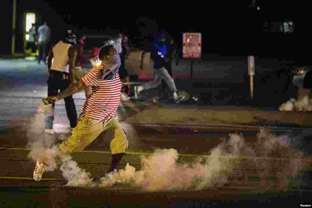 A protester picks up a gas canister to throw back towards the police after tear gas was fired at demonstrators in Ferguson, Missouri, Aug. 17, 2014.