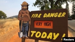 Sebuah rambu di pinggir jalan memperingatkan ancaman kebakaran hutan, yang dipicu oleh berlanjutnya udara panas, di luar kota Colfax, Califormia, 4 Agustus 2018 (foto: Reuters/Jim Christie)