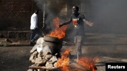 Un manifestant opposé au troisième mandat de President Pierre Nkurunziza fait un geste devant une barricade de flammes à Bujumbura, Burundi, jeudi 2015. 