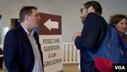 Farmer Jerome Regnault, left, answers questions posed by Germain Milet, right, about his trade. (Lisa Bryant/VOA)