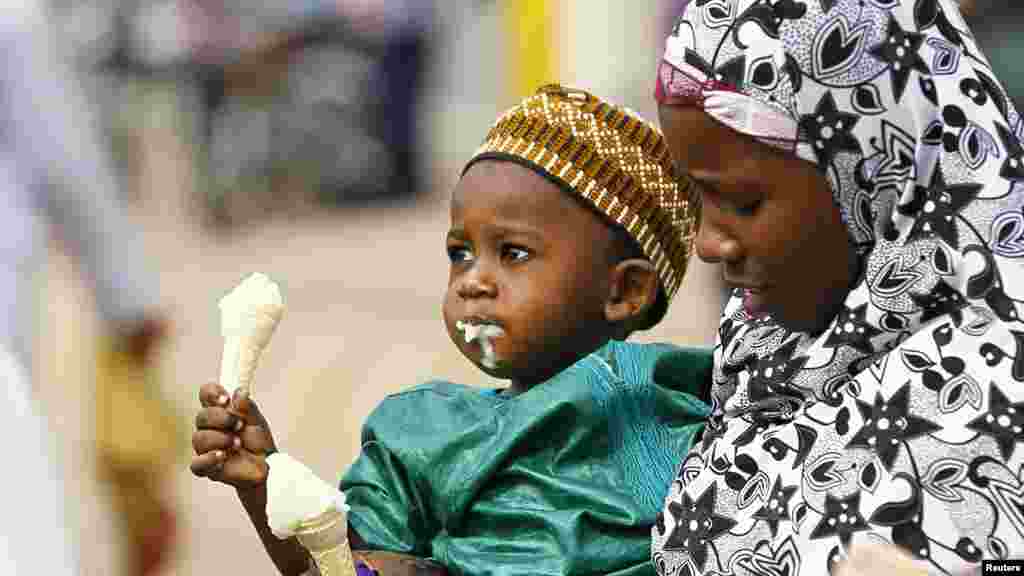 A woman carries a boy eating ice cream after Sallah prayers in Abuja.