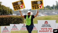 A UAW supporter sings as she tries to beat the hot sun outside an employee vehicle entrance at the Nissan vehicle assembly plant in Canton, Miss., Aug. 4, 2017. 