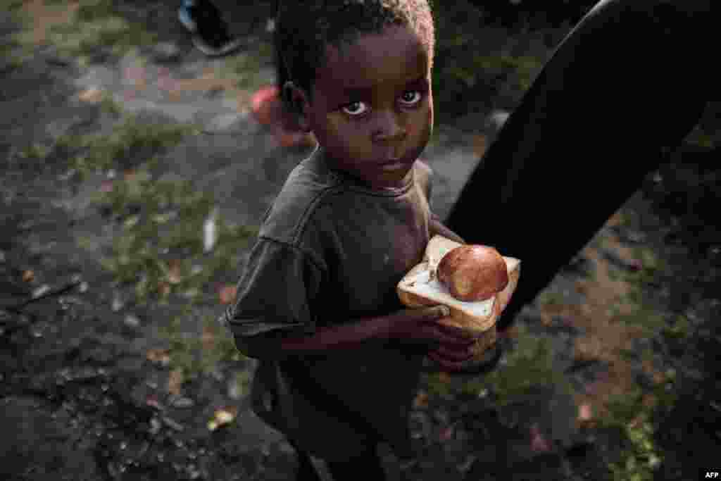 Um menino olha para câmara fotográfica depois da distribuição de comida de um supermercado local, num centro de evacuação no Dondo, cerca de 35km norte da Beira, Moçambique,&nbsp; 27 de Março, 2019.