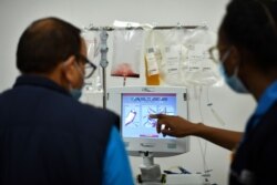 El personal revisa un monitor cuando un donante administra plasma sanguíneo en un centro de donantes de plasma.