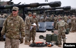 FILE - U.S. troops check military equipment after their deployment to Poland for military exercises in Drawsko Pomorskie training area, Poland, March 21, 2019.