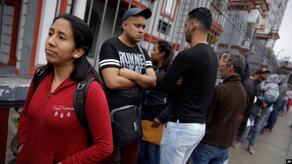 Migrantes venezolanos aguardan frente a la embajada de Venezuela en Lima, PerÃº, el martes, 4 de septiembre de 2018.