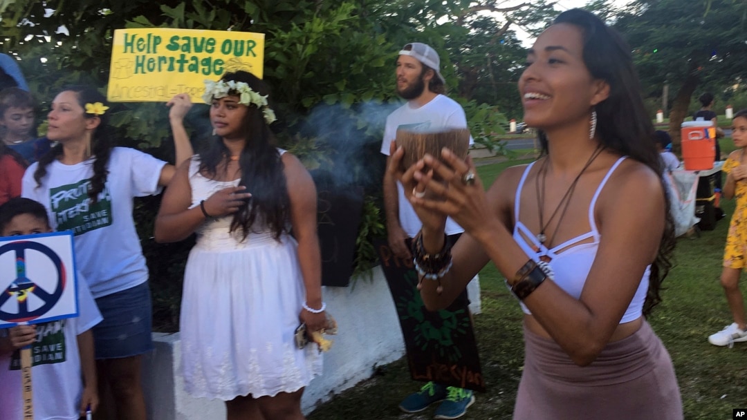 Eva Aguon Cruz, 30, holds a cup with burned flower as a ritual to call for protections from the spirits as about a hundred people gather at Chief Kepuha Park in Hagatna, Guam, for a rally for peace, Aug. 14, 2017. The threatened missile attack by North Korea on Guam has prompted calls for peace from the island's indigenous people, who are weary of yet another conflict after enduring centuries of hostilities. 