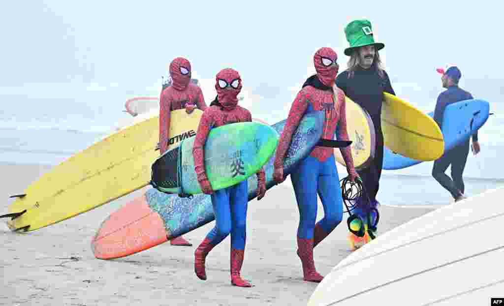 Surfers arrive in costume to surf the waves on a foggy morning at Newport Beach, California, Oct. 26, 2024, to take part in an annual tradition of surfing in costumes.