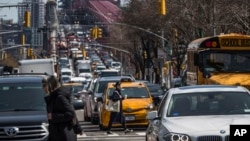 FILE - Pedestrians cross Delancey Street as traffic from Brooklyn enters Manhattan over the Williamsburg Bridge, March 28, 2019, in New York. The Trump administration on Feb. 19, 2025, ordered a halt to a New York City fee system that thins traffic and funds mass transit.