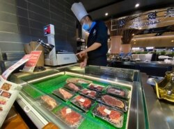 A worker weighs beef products on sale at a food court in Beijing, Aug. 28, 2020. China blocked imports from an Australian beef producer on Friday after reporting a banned drug was found in its meat.