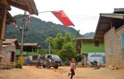 A girl runs across the street in Khokkham, one of six villages in northern Laos to be entirely flooded by the construction of the Luang Prabang dam. (Zsombor Peter/VOA)