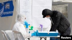 A paramedic in a protective suit helps a man as he prepares to vote in a special polling station, in Ashkelon, Israel, March 2, 2020. 