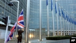 FILE - A member of protocol hoists the British flag outside EU headquarters in Brussels, Belgium, Dec. 4, 2017.