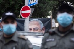 Polisi berjaga-jaga saat pengunjuk rasa anti-pemerintah Israel meneriakkan slogan di luar kediaman resmi Perdana Menteri Benjamin Netanyahu pada hari persidangan korupsi awalnya dijadwalkan sebelum ditunda, di Yerusalem, 13 Januari 2021.