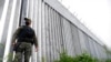 FILE - A policeman patrols alongside a steel wall at Evros River, near the village of Poros, at the Greek -Turkish border, Greece, May 21, 2021.