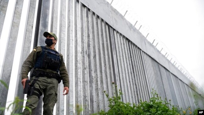 FILE - A policeman patrols alongside a steel wall at Evros River, near the village of Poros, at the Greek -Turkish border, Greece, May 21, 2021.