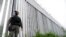 FILE - A policeman patrols alongside a steel wall at Evros River, near the Greek village of Poros, at the Greek-Turkish border, May 21, 2021.