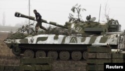 FILE - A member of the self-proclaimed Donetsk People's Republic forces walks atop a self-propelled artillery gun during tactical training exercises in Ukraine's Donetsk region, Feb. 4, 2016. Despite a peace deal, skirmishes between Kyiv forces and pro-Russia separatists continue in eastern Ukraine.