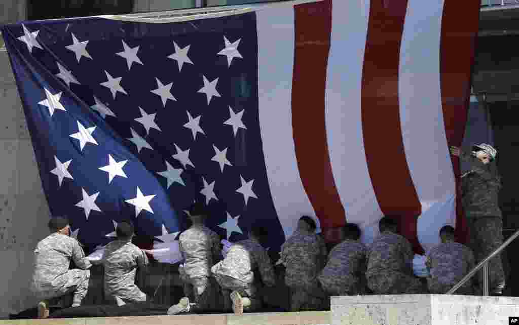 A U.S. flag is removed because of high winds prior to a memorial ceremony for shooting victims that President Barack Obama will attend in Fort Hood, Texas. Last week&#39;s shooting rampage left four dead and more than a dozen injured.