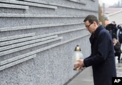 Polish Prime Minister Mateusz Morawiecki places a candle at a memorial wall with names of some of the Poles who saved Jews during the Holocaust, at the Ulma Family Museum of Poles Who Saved Jews during WWII, in Markowa, Poland, Feb. 2, 2018.