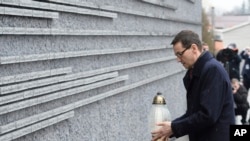 Polish Prime Minister Mateusz Morawiecki places a candle at a memorial wall with names of some of the Poles who saved Jews during the Holocaust, at the Ulma Family Museum of Poles Who Saved Jews during WWII, in Markowa, Poland, Feb. 2, 2018. 