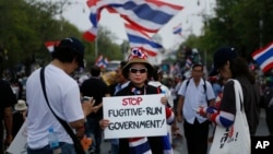 A protester holds a placard denouncing the government outside the government house in attempts to "shutdown" Bangkok, Thailand, Feb. 17, 2014.