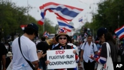 A protester holds a placard denouncing the government outside the government house in attempts to "shutdown" Bangkok, Thailand, Feb. 17, 2014.