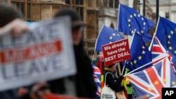 FILE - Pro- and anti-Brexit demonstrators wave placards and flags outside the Houses of Parliament in London, Britain, Dec. 18, 2018.