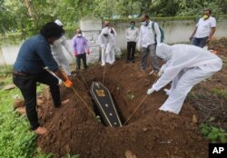 23일 인도 뭄바이의 묘지에서 장례식 직원들이 신종 코로나바이러스 감염증 사망자 시신이 든 관을 땅에 묻고 있다.