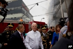 Peru's President Pedro Pablo Kuczynski walks to inspect firefighting efforts at a warehouse in Lima, June 23, 2017.