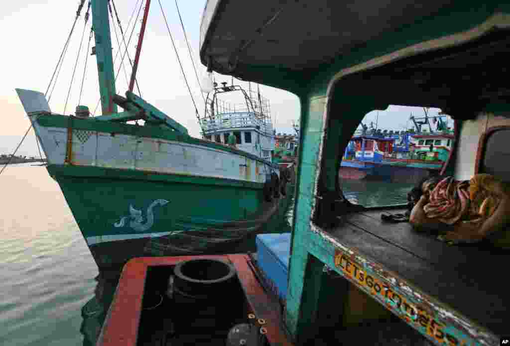 Seorang nelayan tidur di perahunya, sebelah kapal yang membawa para Muslim Rohingya dari Myanmar dan migran dari Bangladesh di pelabuhan Lhokseumawe, Aceh (14/5). ​(AP/Binsar Bakkara)