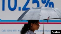 FILE - A woman walks past an advertisement of a private bank in Colombo, Sri Lanka, Sept. 23, 2014.