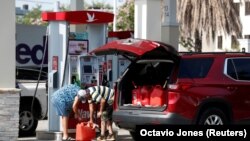 Un couple remplit plusieurs réservoirs de gaz de 5 gallons dans une station-service de Wawa, le 12 mai 2021.