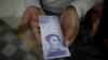 Una mujer muestra un billete nuevo de 500.000 bolívares después de retirarlo de un banco en Caracas, el 16 de marzo de 2021. Foto: AP.