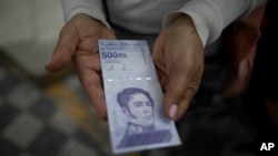 Una mujer muestra un billete nuevo de 500.000 bolívares después de retirarlo de un banco en Caracas, el 16 de marzo de 2021. Foto: AP.