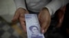 Una mujer muestra un nuevo billete de 500.000 bolívares después de retirarlo de un banco en Caracas, Venezuela, el 16 de marzo de 2021.