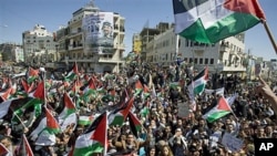 Palestinians wave flags and chant slogans during a rally calling for a reconciliation between the rival Palestinian leading factions Hamas in Gaza and Fatah in the West Bank, in the West Bank city of Ramallah, March 15, 2011