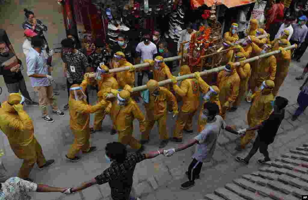 Nepalese devotees wearing protective gear as a precautionary measure against the coronavirus carry the chariot during Pachali Bhairav festival in Kathmandu.