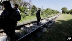 Soldados vigilan las vías del tren cerca de Guadalajara para evitar que migrantes se suban a él.