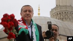 Turkish Prime Minister Recep Tayyip Erdogan throws roses to his supporters after a speech in Istanbul, June 11, 2011.