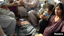 Relatives and members of civilians sit next the body of a man who was killed during clashes between Afghan security forces and the Taliban in Kunduz, Afghanistan, Nov. 3, 2016. 